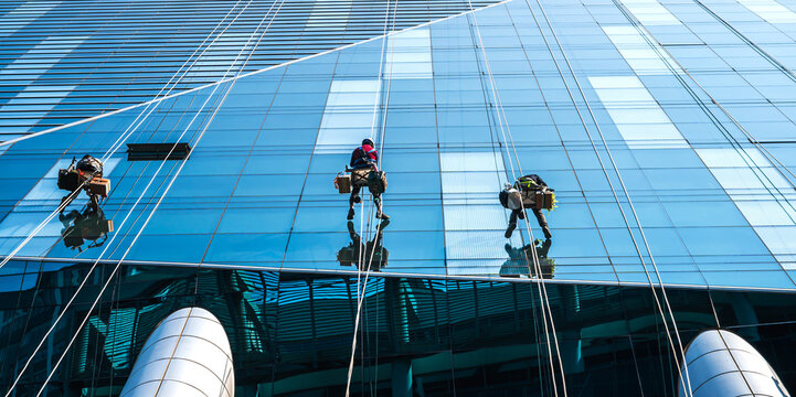 Group of high rise workers hanging on access rope cleaning highrise glass building in Seoul, South Korea