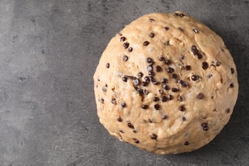 Raw dough with chocolate chips on grey table, top view. Space for text