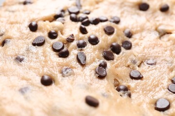 Raw dough with chocolate chips as background, closeup
