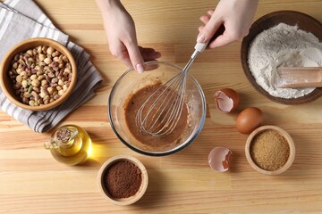 Woman making chocolate dough at wooden table, top view