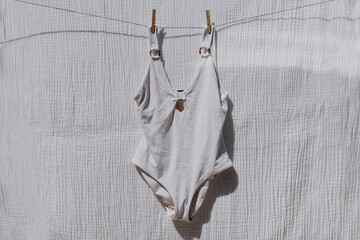 Bikini swimsuit hanging on rope over white cloth with strong shadows. Sunny day sunbathing. Chic fashion - 785556123