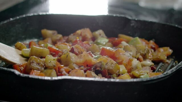 Vegan Ratatouille with Stewed Eggplants and Peppers. The chef prepares baked vegetables and homemade vegetable ratatouille in a frying pan. A delicious combination of seasonal vegetables creates a