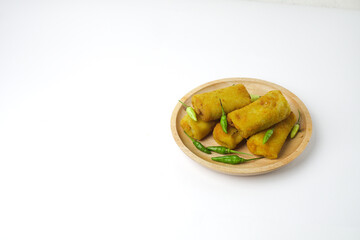 Risoles, a snack from Indonesia served with a little green chili in a wooden plate. Risol and green chilies isolated on a white background