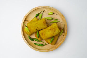 Risoles, a snack from Indonesia served with a little green chili in a wooden plate. Risol and green...