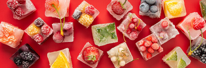 Red background with ice cubes with frozen berries and fruits and mint, banner