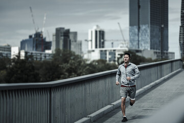 A man running up on footbridge in the city center park for cardio workout.  Health and Lifestyle in...