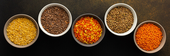 Multicolored lentils in bowls banner, yellow and brown, green and orange lentils, healthy legumes, top view, copy space