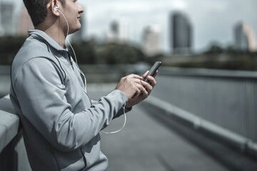 sport man listen music earphone and  use smartphone Fitness application, social media, listening to music. Health and Lifestyle in big city life concept.