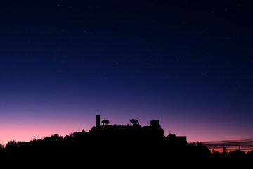 Dawn breaking over the silhouette of the medieval village of Turenne in the Correze department of...