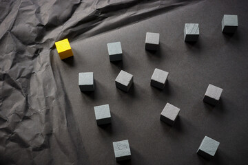 Crumpled paper and a yellow cube as a leader overcomes obstacles.
