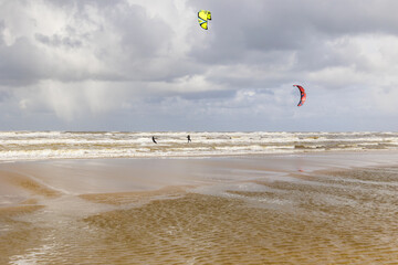 Water sports enthusiasts go kitesurfing in the waves by the sea with wild waves in the Dutch town...