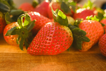 appetizing ripe red fresh strawberries, Fragaria, on wooden board, illuminated rays sun, fresh...