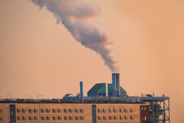 dramatic view factory with steam coming out of chimney, rising into sky, power and might of modern...