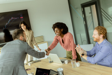 Jubilant business professionals celebrating success with a handshake in a modern office meeting room