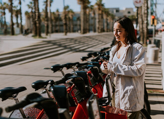 A serene spring afternoon in Barcelona with a smiling woman renting a bicycle - obrazy, fototapety, plakaty