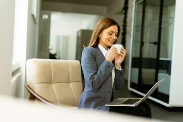 Elegant businesswoman enjoying a peaceful coffee break on sunny office morning