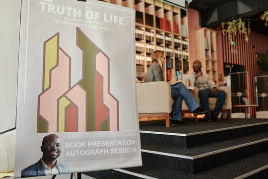 Presentation poster of famous author and his new book standing by stage with show host interviewing publicist