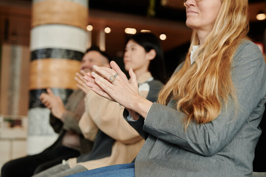 Cropped shot of young woman with long blond hair clapping hands after presentation of new book of her favorite author