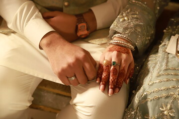 hands of the bride and groom,  rings bangles, watch, traditional costume