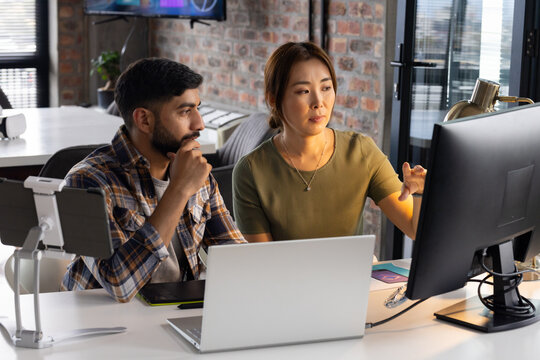 Asian mature woman and young man view computer screen in a modern business office