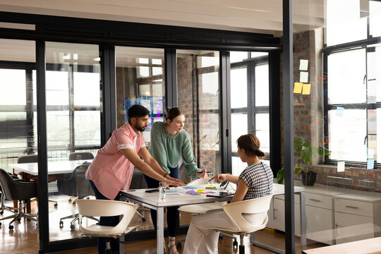 Diverse team discussing app design in a modern business office, senior Asian woman leading