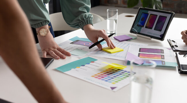 A diverse team is discussing app design, pointing at color swatches in a modern business office