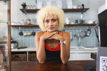 Biracial barista with curly blonde hair resting chin on hands