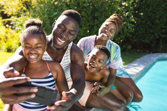 African American family enjoying time by pool at home, taking selfie