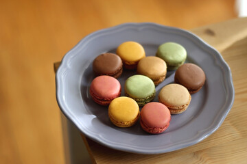 Purple plate filled with pastel macarons on wooden table. Selective focus.
