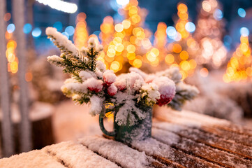 Outdoors shot of a wooden table with Christmas decoration covered with snow.