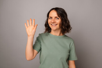 Studio portrait of a beautiful mature smiling woman waving at the camera.