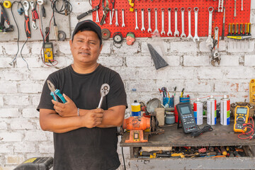 Portrait of a mechanic standing holding tools in a garage