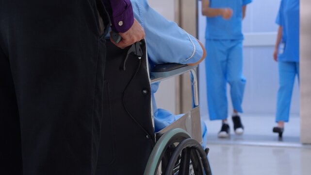 Young asian man pushing button with elevator while elderly father sitting on wheelchair at hospital, senior dad sitting on wheelchair and son pushing wheelchair to elevator, medical and insurance.