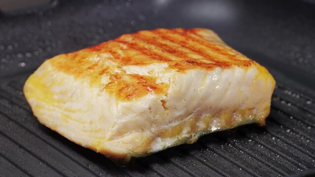 Cooking fillet sturgeon fish on grill or frying pan with oil close-up. Roast healthy food concept. Fry sturgeon, hake, cod fish steak pieces fillet with spice. Healthy diet food