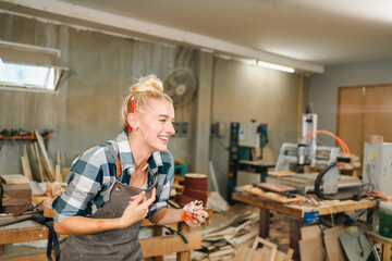 In the carpenter's shop, a professional woman crafts wooden furniture, using tools with skill in her woodwork occupation, showcasing industry prowess.