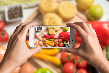 Woman hands taking a photo of colorful vegetables and noodles on wooden background. Food concept.