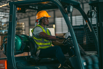 A man in a yellow safety vest and a hard hat is sitting in a forklift cab