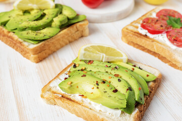 Sliced avocado on toast bread with spices on white wooden background. Food concept.
