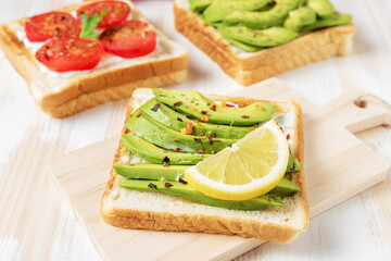 Sliced avocado on toast bread with spices on white wooden background. Food concept.