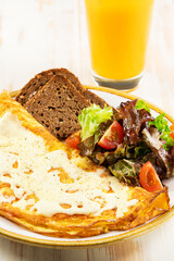Omelette with cheese, tomatoes and green with orange juce on wooden background. Tasty freshly breakfast. - obrazy, fototapety, plakaty