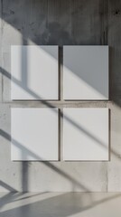 a mockup blank white canvases hang side by side on a concrete wall, illuminated by soft light casting subtle shadows
