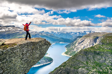 Hiker woman stands at rock and looks at aerial view in the mountains. Amazing nature view on the way to Trolltunga. Location: Scandinavian Mountains, Norway, Odda. Beauty world. The feeling of freedom
