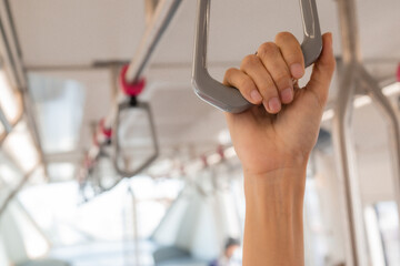 A close-up view of a person's hand gripping a handrail in a train, symbolizing safety and stability...