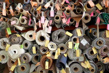 A variety of furniture fabric, rolled up, is stored on racks in the warehouse of a furniture...