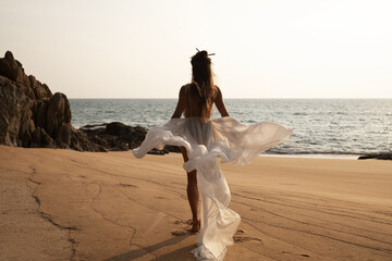 Beautiful bride in a flowing white dress dances on the beach