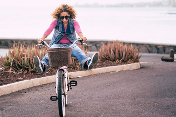 One young lady riding bike alone on the street with ocean coastline view. Outdoor leisure activity...