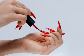 Application of Red Nail Polish on Stiletto Nails on Gray Background