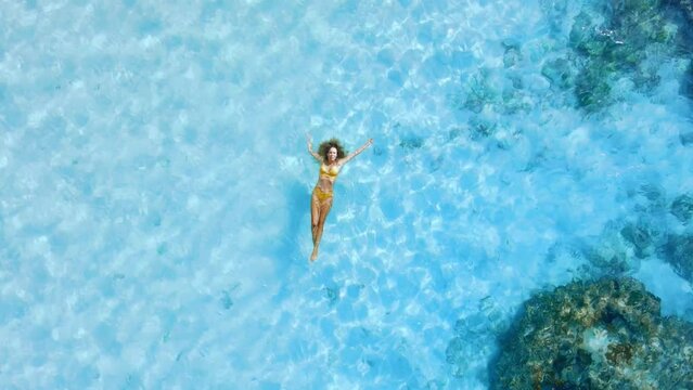 Woman swims and relaxing in tropical blue sea. Aerial top down view, vacations in tropics