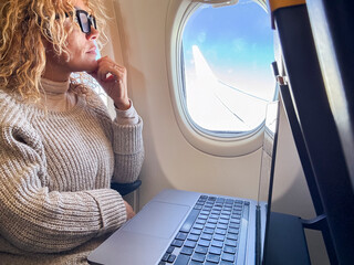 Middle aged business woman working on laptop while sitting on airplane. Travel and business trip...