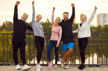 Team of athletes posing hands raising happiness autumn park spirit of friendship lifestyle of...